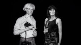 Black and white photo with prolific artist Andy Warhol standing on the left and photographer